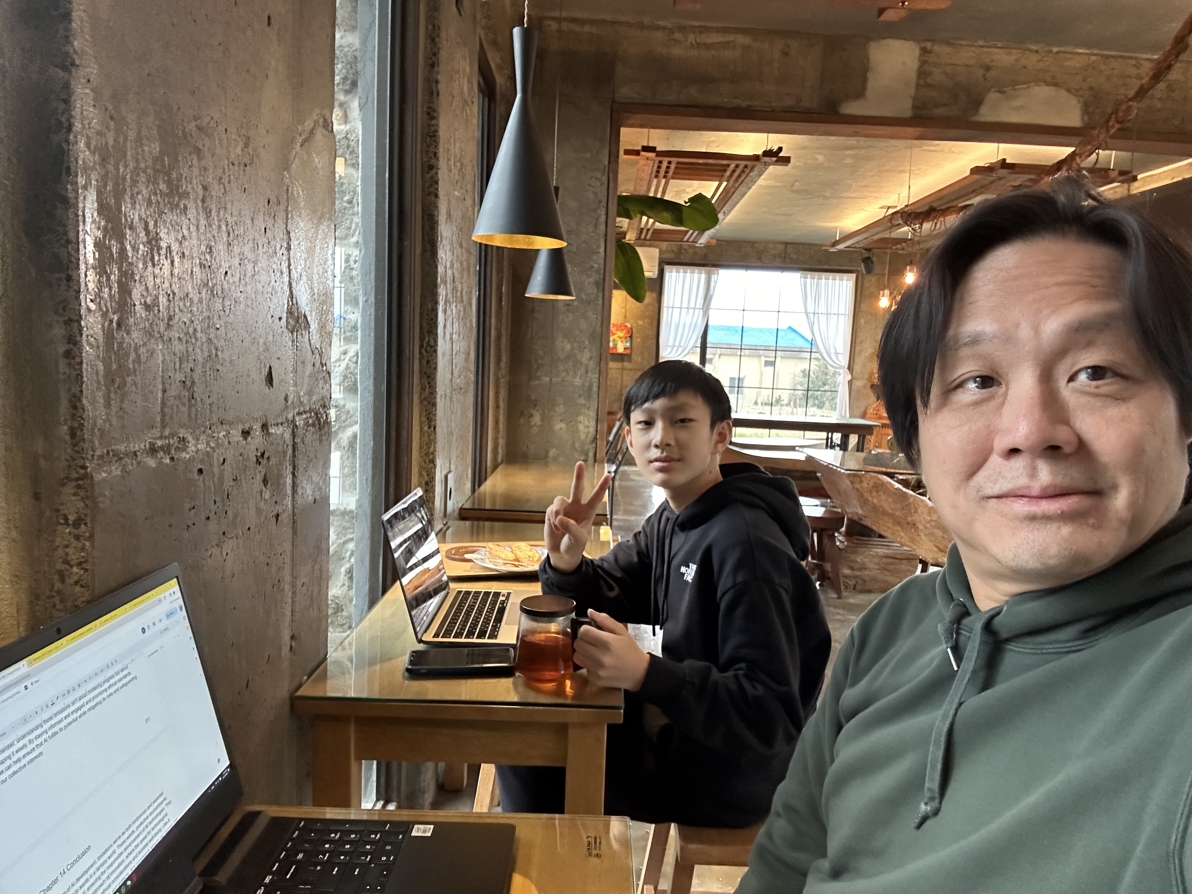 Frank and Ryan Ng working together beside their laptops during the early development of Hey AI, Let’s Talk!